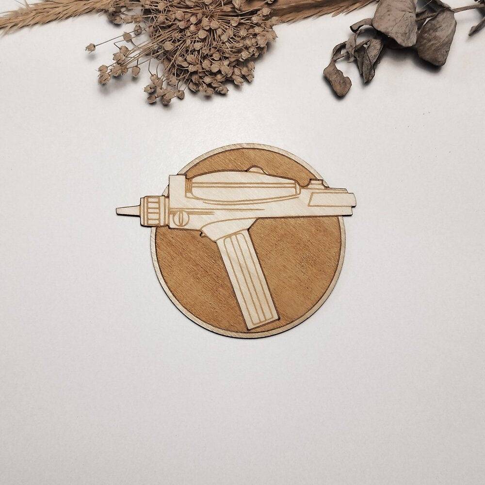 Six wooden coasters featuring laser-etched Star Trek motifs, arranged on a rustic wooden tabletop